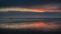 People silhouettes walking along the Wadden Sea in Buesum during dramatic sunset