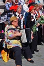 People sing war songs. A woman plays accordeon.