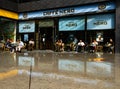 People sit outside the exterior of a Caffe Nero food retail chain cafe in central London with blue signage