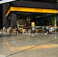 People sit outside the exterior of a Leon food retail chain cafe in central London with orange signage