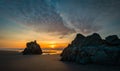 People sit on rock watching dramatic sunset at Oregon coast. Royalty Free Stock Photo