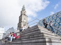 People sit on steps near central square in front of martini tower in groningen