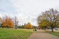 People sit on wooden bench and walk in Hyde Park London