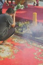 People sit and worship Buddha with incense and flowers on carpet floor