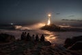 people sitting on the beach, watching a lighthouse beam light over the waves