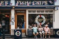 People sitting on a bench outside Poppie`s Fish & Chips shop in London, UK.