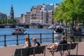 People sitting on benches at Amstel River waterfront
