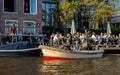 People sitting in Cafe restaurant on the canal in Amsterdam with parked small city tour boat, the Netherlands, October 13, 2017 Royalty Free Stock Photo