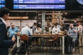 People sitting at a cafe, waiting for their trains under the departure board inside St. Pancras station, London, UK.