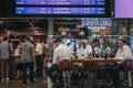 People sitting at a cafe, waiting for their trains under the departure board inside St. Pancras station, London, UK.