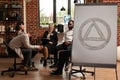 People sitting in circle at group therapy session while having aa meeting sign in office Royalty Free Stock Photo