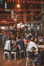 People sitting and eating street food at the evening Temple Street Market in Hong Kong