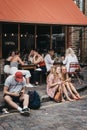 People sitting on the ground on Erza Street, relaxing after visiting Columbia Road Flower Market, London, UK.