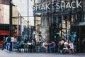 People sitting at the outdoor tables of Shake Shack in Victoria station, London, UK Royalty Free Stock Photo