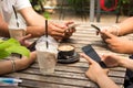 People are sitting on the phone and drinking coffee on a wooden table in a restaurant.