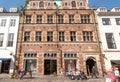 People sitting and relaxing on bench past beautiful brick facade of historical house