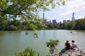 People sitting on the rocks near the pond in Central Park, New York