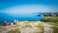 Family is sitting on a cliff at Tintagel castle in Cornwall, England with the Atlantic Ocean coastline Royalty Free Stock Photo