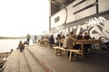 People sitting at wooden tables at a cafe and drinking beer, river and Kiev hills on a background