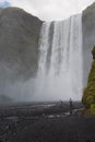 People by Skogafoss waterfall on Iceland golden circle. Couple visiting famous tourist attractions and landmarks