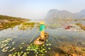 People with small boat on Van Long pond, Ninh Binh province, Vietnam