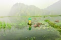 People with small boat on Van Long pond, Ninh Binh province, Vietnam