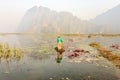 People with small boat on Van Long pond, Ninh Binh province, Vietnam