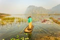 People with small boat on Van Long pond, Ninh Binh province, Vietnam