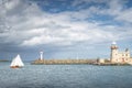 People on a small sailboat exiting Howth marina, passing Howth Lighthouse and per