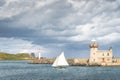 People on a small sailboat exiting Howth marina, passing Howth Lighthouse and per