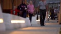 People spend time in the modern park in the evening. Stock footage. Families walking in the city park near the wooden