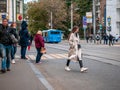 People stand near a crosswalk waiting for a green traffic light. Typical cityscape in the center of the capital. Autumn weather