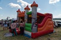 People stand near an inflatable children`s trampoline in the form of a castle during the festival Karatag on the shore of Lake Royalty Free Stock Photo