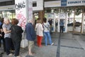 People stand in a queue to use the ATMs of a bank