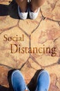 People stand on the road with the word social distancing in between. Concept of staying physically apart for infection control