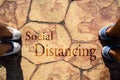 People stand on the road with the word social distancing in between. Concept of staying physically apart for infection control