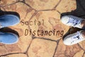 People stand on the road with the word social distancing in between. Concept of staying physically apart for infection control