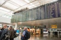 People stand under flight departure board