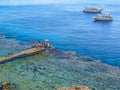 People stand on a wooden pier and two tourist boats in blue water Royalty Free Stock Photo