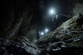 People Standing Inside of a Cave, A journey of a nightime climb, with climbers using headlamps to light their path up the rock