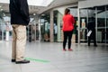 People standing in line front of bank/store due to coronavirus pandemic safety guideline.COVID-19 safe social distancing practice.