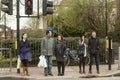 People are standing at a pedestrian crossing, waiting for the light to switch to green