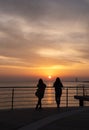 People standing on a pier enjoying dramatic orange sunset at the sea Royalty Free Stock Photo