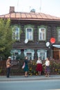 People standing on the street of russian village - a pretty woman in emerald skirt dancing