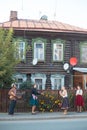 People standing on the street of russian village - a pretty woman in emerald skirt dancing by the music from balalaika