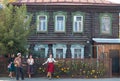 People standing on the street of russian village - a woman in red skirt dancing by the music from balalaika