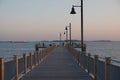 People standing on a wooden dock extending into the sea at sunset. Royalty Free Stock Photo