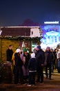 People standing by wooden huts at a Christmas market in the Plac Wolnosci square at night in Poznan.