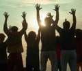 People stands on against a sun with heaved up hands. Royalty Free Stock Photo