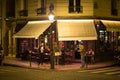 People at a street restaurant at night in Paris